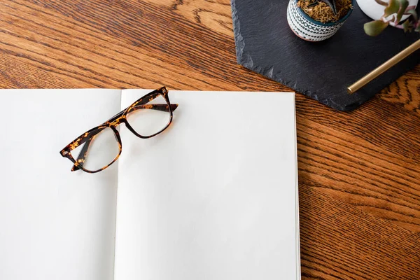 Glasses and a Blank Notebook on Warm Wood