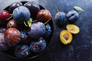 Siyah arka planda toplanmış taze eriklerin olduğu kaseyi kapat..