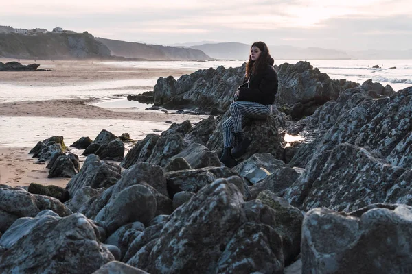 女人坐在海边的岩石上 — 图库照片
