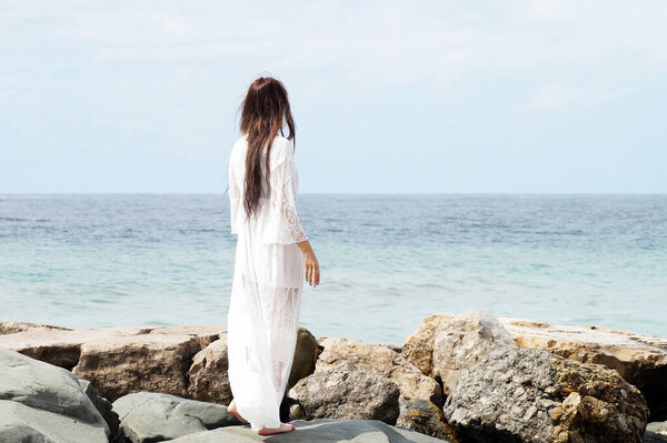 A woman stands on the seashore and looks into the distance