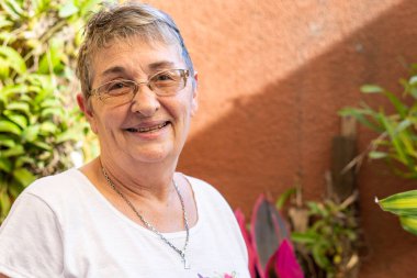 Yaşlı kadın gözlükleriyle gülümsüyor.