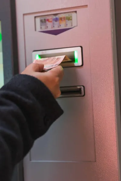Male hand inserting money at electronic machine in parking