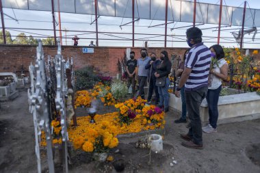 Cholula, Meksika; 11-02-2021 Mezar kenarında dua eden aileler Puebla 'daki ölüm gününü kutlamak için cempasuchil çiçekleriyle güzelce süslenmiş. Dia de muertos. Seçici Odaklanma