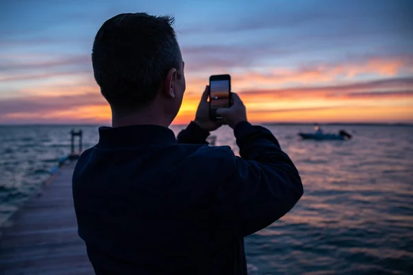 男人用智能手机拍摄大海上美丽的落日 — 图库照片