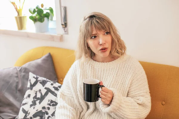 Woman White Sweater Looks Worried Holding Black Cup — Stockfoto