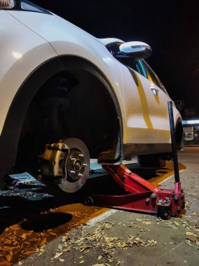 Lastik servisinde tekerlekleri olmayan beyaz araba.