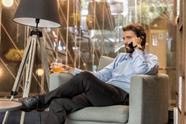 Çekici bir iş adamı, ofisinde içkiyle bir telefon görüşmesi yapıyor.