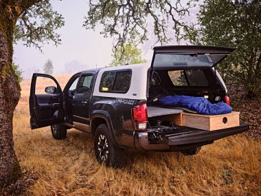 A Toyota Tacoma truck set up for camping in the woods on a ranch clipart