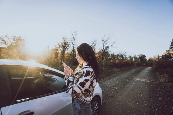 Kvinna Tittar Mobilen Bredvid Bil Väg Mellan Träd — Stockfoto