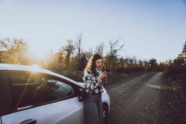 Vrouw Kijkt Naar Mobiele Naast Een Auto Een Weg Tussen — Stockfoto