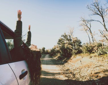 Kadın arabanın camındaki ağaçlar arasındaki yolda.