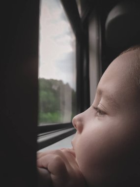 Küçük çocuk trenin penceresinin yanında duruyor.