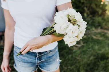 Close up of woman holding bouquet of freshly cut white roses