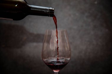 Glass of red wine in half on a dark background.
