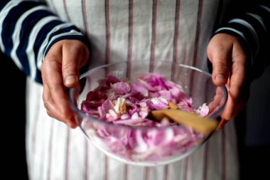 Mutfakta pembe gül yaprağı reçeli yapan kadın.