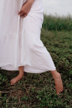 a young girl in a white dress and a skirt stands on a green grass