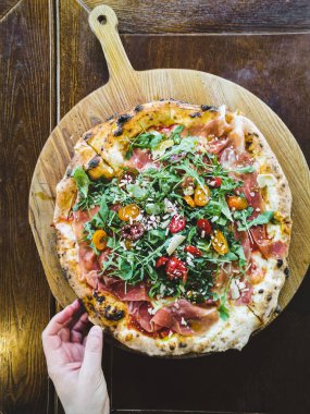 Prosciutto, roka ve parmesanlı bir dilim pizza alır.