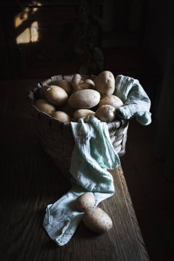 Bahçeden gelen patatesler kırsal ahşap mutfak masasında bir sepetin içinde