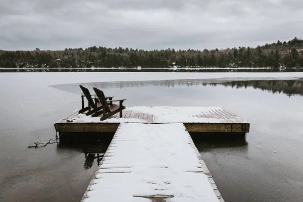Ξύλινη Αποβάθρα Καλυμμένη Χιόνι Καρέκλες Μισή Παγωμένη Λίμνη Στον Καναδά — Φωτογραφία Αρχείου