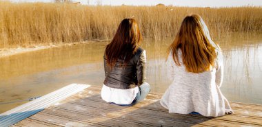 Genç ve güzel kadınlar iskelede oturuyor.