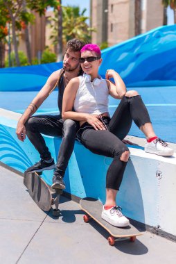 Genç çift kaykaydan sonra parkta oturuyor.