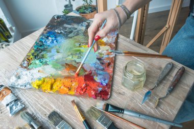 Kadın sanatçı palette boya karıştırıyor