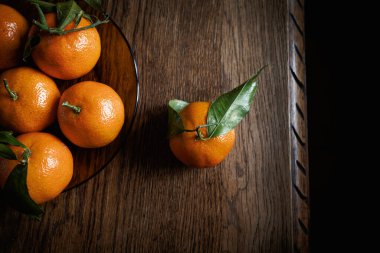 Eski ahşap bir masada taze ve olgun mandalinalar.