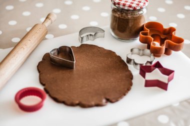 Kesme tahtasında çikolata hamuru, merdane ve bisküvi kalıpları.