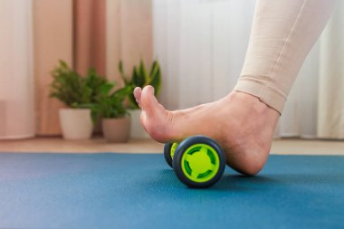 Ayağın üst kemerini bir masaj rulosuyla yuvarlıyor.