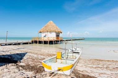 Holbox Adası 'ndaki balıkçının rıhtımının panoramik manzarası ve tropikal sahilde bir balıkçı teknesi.
