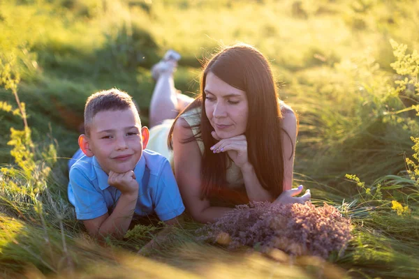 母と息子は日没時に草の上に横になり 母は息子を見て — ストック写真