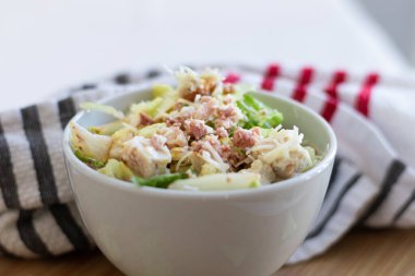 Beyaz kasede tavuk ve domuz pastırması olan bir salata yakın plan..