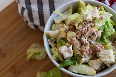Beyaz kasede tavuk ve domuz pastırması olan bir salata yakın plan..