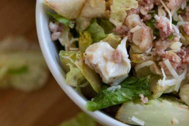 Beyaz kasede tavuk ve domuz pastırması olan bir salata yakın plan..