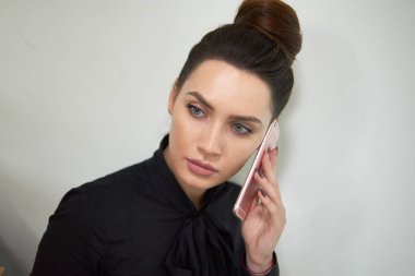 Ofiste cep telefonuyla konuşan genç profesyonel bir bayan.