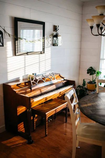 Piano in dining room with window light, shiplap walls, and table