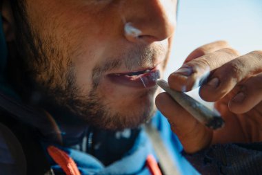 Açık havada esrar içen bir gencin yakın çekimi.