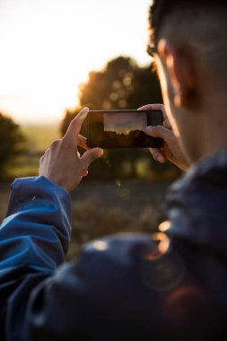 Akıllı telefonuyla fotoğraf çeken genç bir çocuğun elleri.
