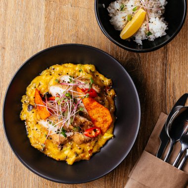 Tahta arka planda siyah tabaklı körili tavuk. restoran menüsü.