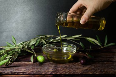 Elleri ahşap masaya zeytinyağı döküyor.