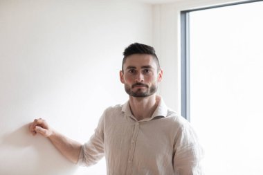 Duvarda kolu olan genç bir adam memnun görünüyor.