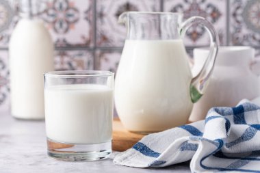 Bardakta süt, arka planda sürahi ve şişe.