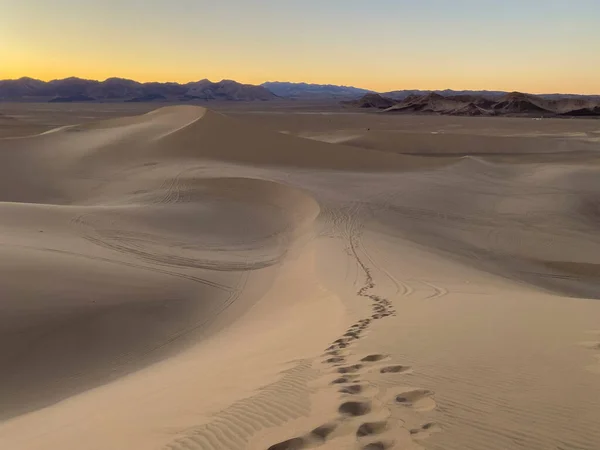 日没時に砂の砂丘に足跡やタイヤトラック — ストック写真