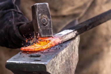 Demirci örs üzerinde metal üzerinde çalışıyor. Yüksek hızda çekim yapıyor.