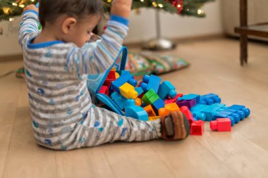 Küçük bebek Noel hediyeleriyle ağaçta oynuyor.
