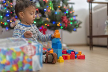 Genç Latin oğlan Noel hediyelerini ağacın yanında yiyor.