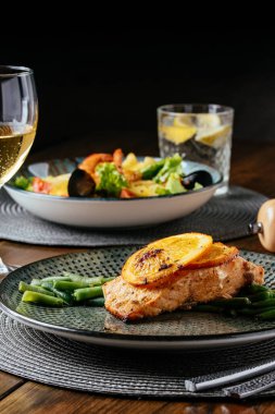 Ahşap arka planda garnitürlü ızgara balık. Restoran menüsü