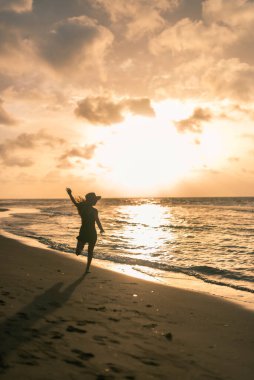 Genç ve çekici Latin kız gün batımında sahilde oynuyor.