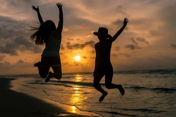 Силуэт Двух Молодых Девушек Прыгающих Веселящихся Закате — стоковое фото
