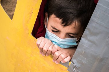 Tıbbi maskeli bir çocuğun portresi, kapalı gözler ifadesi.